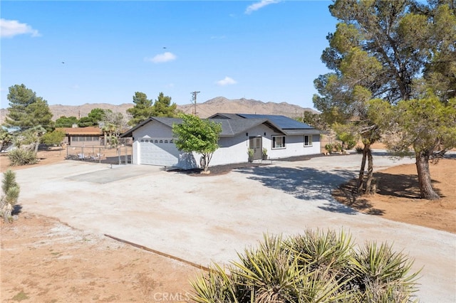 view of front property featuring a mountain view, a garage, and solar panels