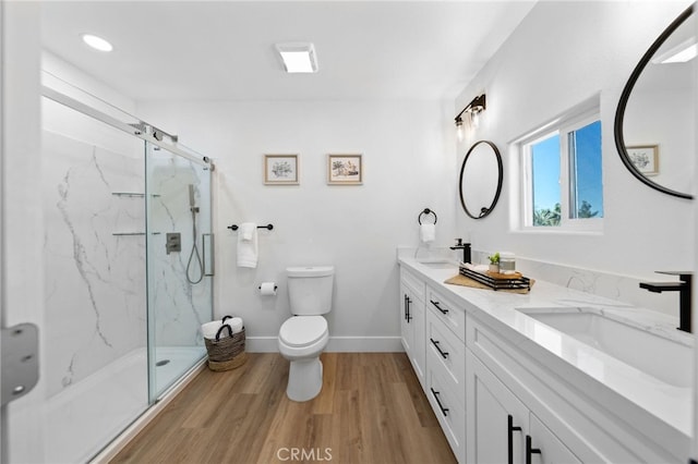 bathroom featuring vanity, wood-type flooring, a shower with door, and toilet