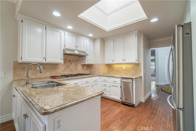 kitchen featuring stainless steel appliances, sink, white cabinetry, kitchen peninsula, and light stone countertops