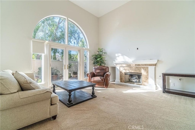 carpeted living room featuring french doors, high vaulted ceiling, and a fireplace