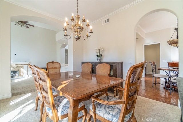 dining area with ceiling fan with notable chandelier, carpet floors, and crown molding