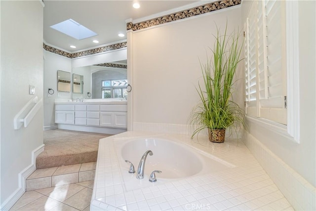 bathroom featuring vanity, tile patterned floors, a skylight, and tiled tub