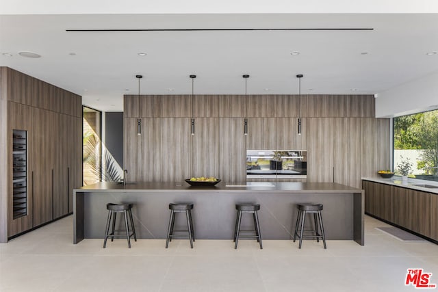 kitchen with a kitchen breakfast bar, light tile patterned floors, wood walls, and a large island