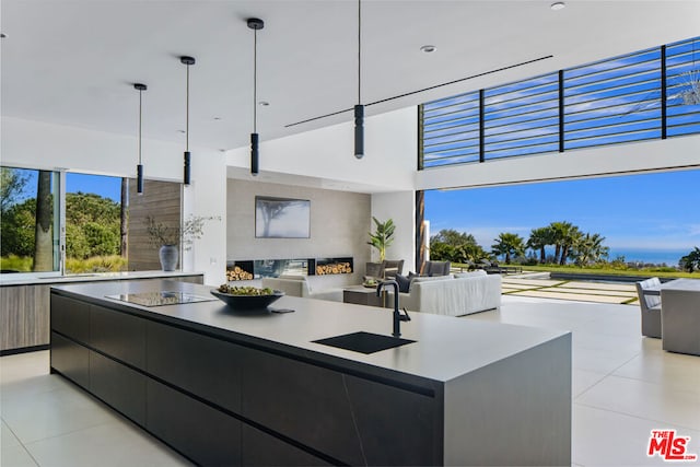 kitchen with light tile patterned floors, sink, hanging light fixtures, and a large island