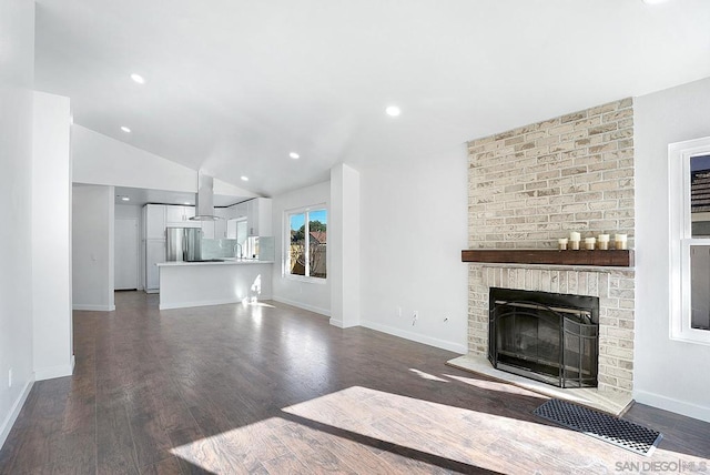 unfurnished living room featuring dark wood-type flooring, a brick fireplace, and lofted ceiling