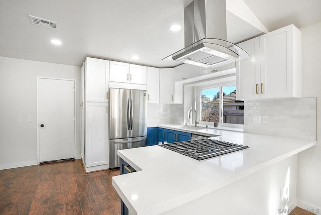 kitchen featuring island exhaust hood, sink, stainless steel refrigerator, white cabinetry, and blue cabinetry