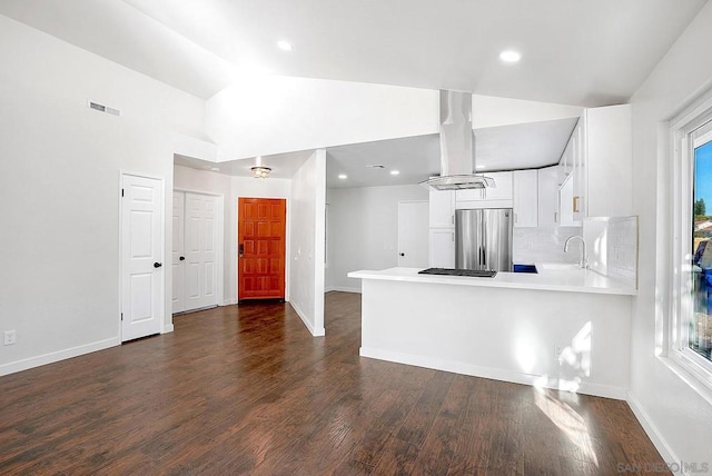 kitchen with white cabinetry, lofted ceiling, kitchen peninsula, and stainless steel refrigerator