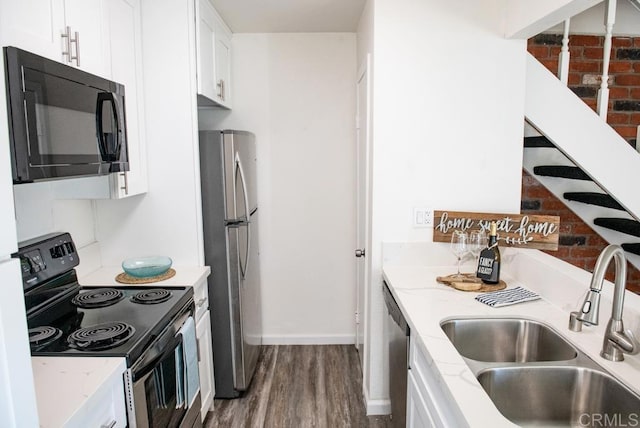 kitchen with light stone countertops, dark wood-type flooring, white cabinetry, stainless steel appliances, and sink