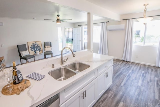 kitchen featuring white cabinets, hanging light fixtures, light stone counters, an AC wall unit, and sink