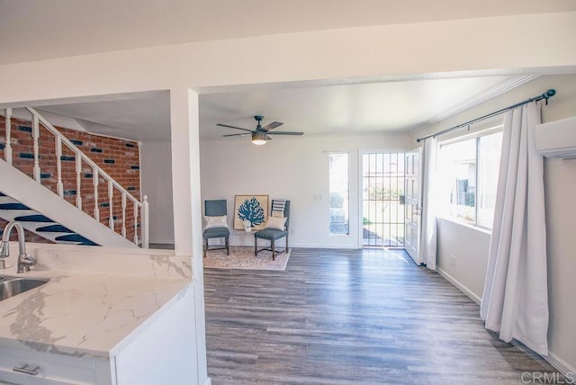 interior space featuring ceiling fan, dark wood-type flooring, crown molding, an AC wall unit, and sink