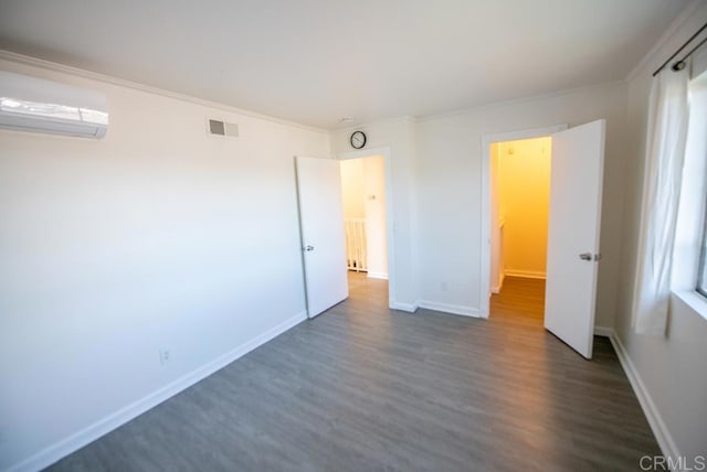 unfurnished bedroom featuring multiple windows, dark hardwood / wood-style flooring, ornamental molding, and a wall mounted air conditioner