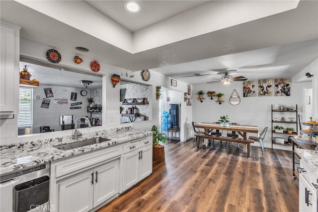 kitchen featuring backsplash, light stone counters, ceiling fan, sink, and white cabinetry