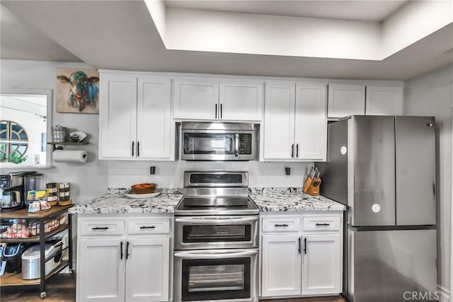 kitchen featuring tasteful backsplash, white cabinetry, and stainless steel appliances