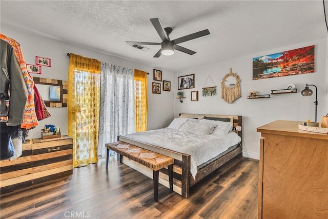 bedroom with ceiling fan, a textured ceiling, and dark wood-type flooring