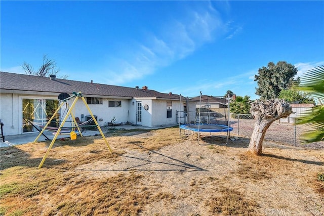 rear view of house featuring a playground and a trampoline