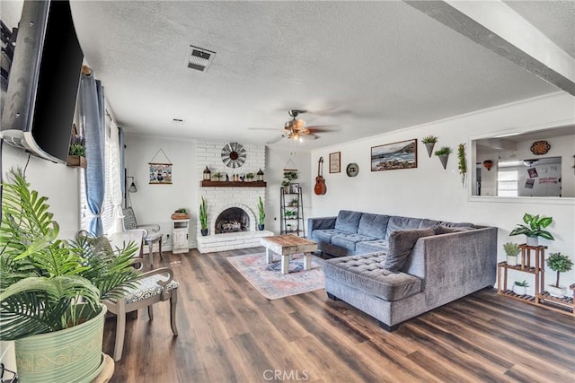 living room with ceiling fan, a fireplace, dark wood-type flooring, and a textured ceiling