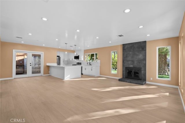 unfurnished living room with sink, light hardwood / wood-style flooring, and french doors