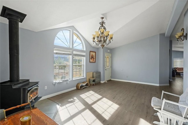 living room featuring lofted ceiling, an inviting chandelier, a wood stove, and hardwood / wood-style floors