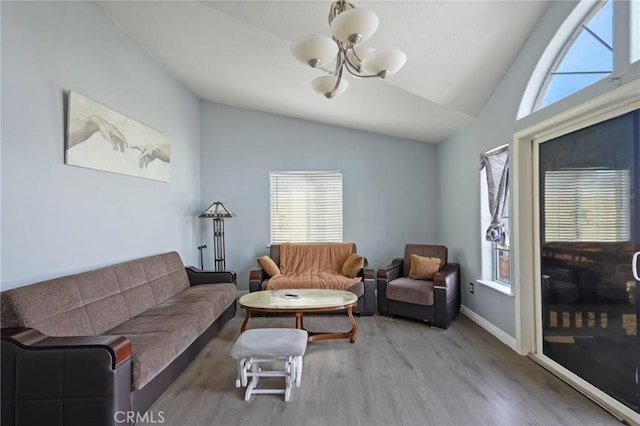 living room featuring lofted ceiling, plenty of natural light, an inviting chandelier, and hardwood / wood-style flooring