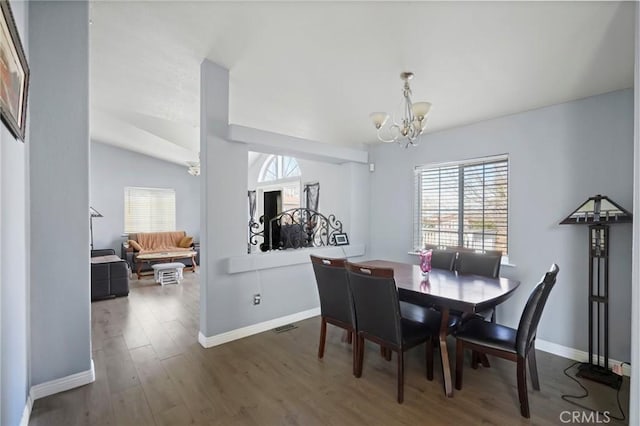 dining area with vaulted ceiling, dark hardwood / wood-style floors, and a chandelier