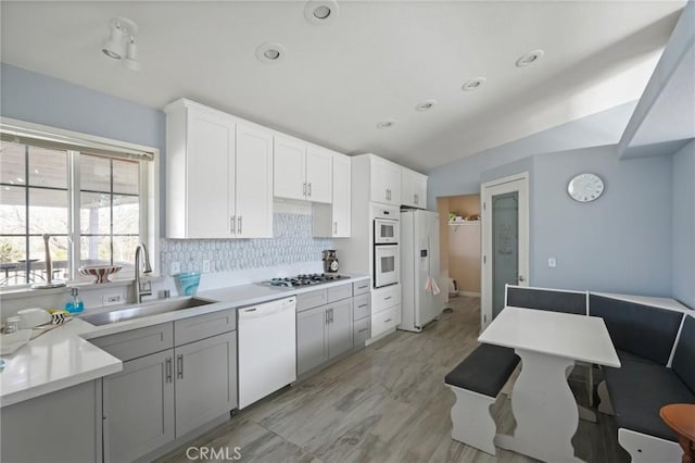 kitchen with decorative backsplash, sink, white appliances, and white cabinets