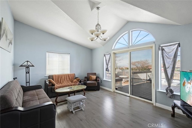 living room featuring dark wood-type flooring, a notable chandelier, and vaulted ceiling