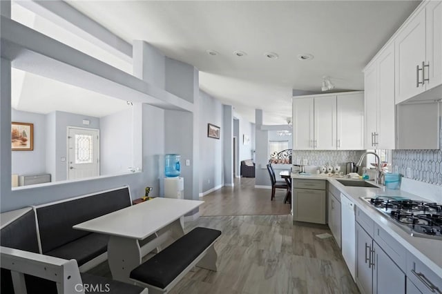 kitchen featuring stainless steel gas stovetop, backsplash, light wood-type flooring, white cabinets, and sink