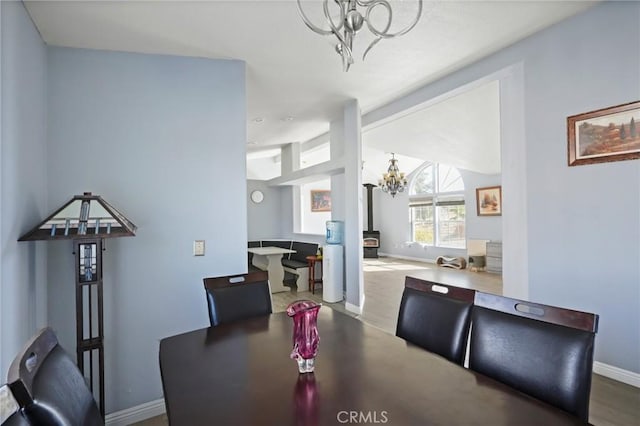 dining area with a wood stove, wood-type flooring, and an inviting chandelier