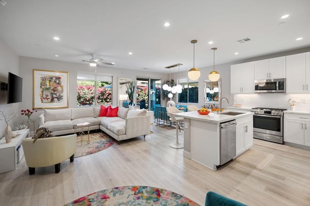 kitchen featuring white cabinetry, ceiling fan, stainless steel appliances, pendant lighting, and sink