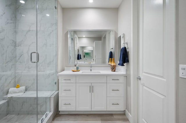 bathroom with a shower with shower door, hardwood / wood-style flooring, and vanity