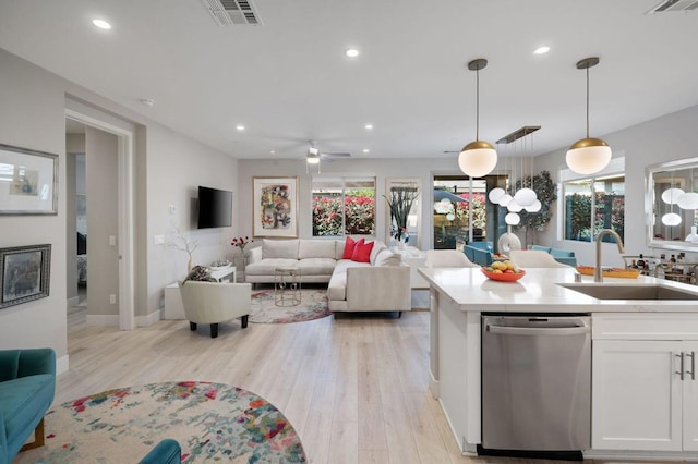 kitchen with decorative light fixtures, dishwasher, light hardwood / wood-style floors, sink, and white cabinets