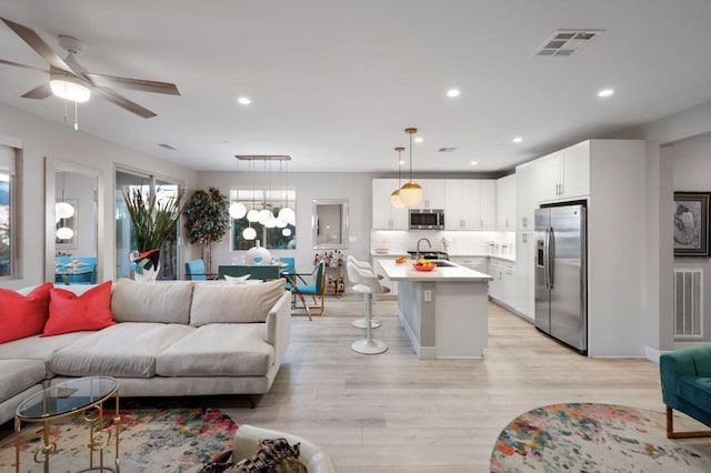 living room with ceiling fan, sink, and light hardwood / wood-style flooring