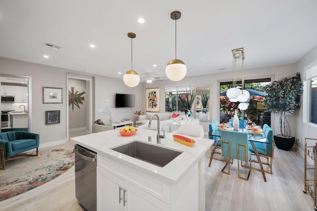 kitchen featuring a center island with sink, stainless steel appliances, pendant lighting, white cabinets, and sink