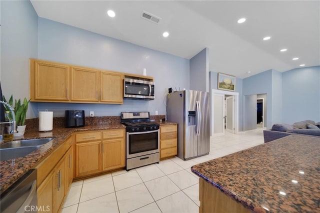 kitchen featuring light tile patterned flooring, stainless steel appliances, vaulted ceiling, and dark stone counters