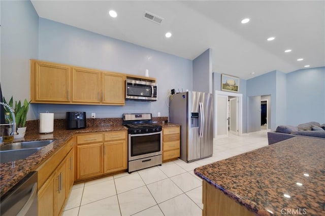 kitchen with stainless steel appliances, dark stone countertops, visible vents, light tile patterned floors, and a sink