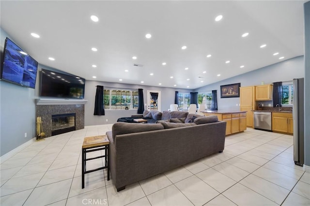 living area with plenty of natural light, vaulted ceiling, a high end fireplace, and light tile patterned floors