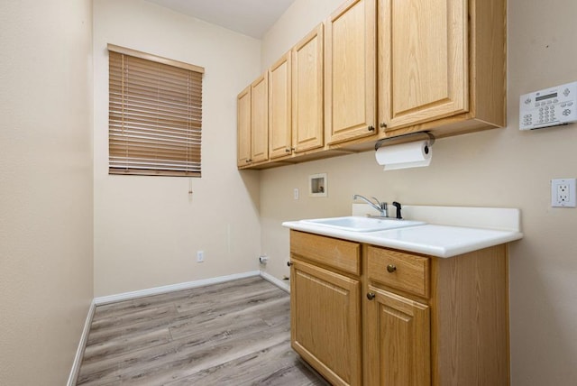 laundry room with washer hookup, sink, light hardwood / wood-style floors, and cabinets