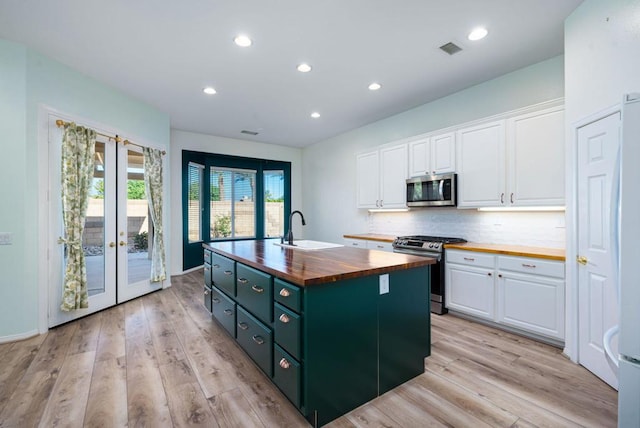 kitchen with white cabinets, appliances with stainless steel finishes, sink, and wooden counters