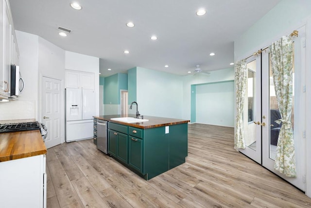 kitchen featuring white cabinets, white refrigerator with ice dispenser, sink, a kitchen island with sink, and butcher block countertops