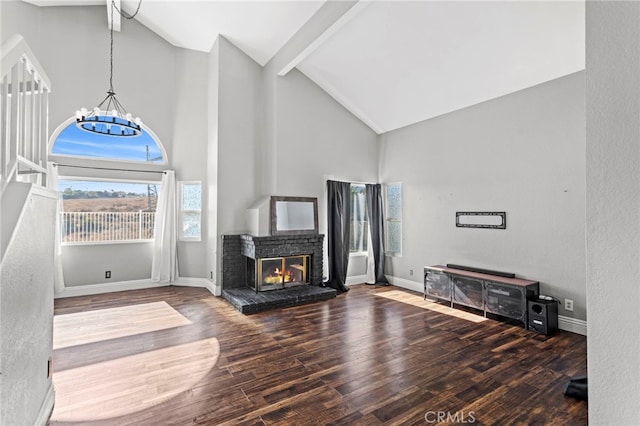 unfurnished living room featuring an inviting chandelier, a brick fireplace, dark hardwood / wood-style flooring, high vaulted ceiling, and beam ceiling