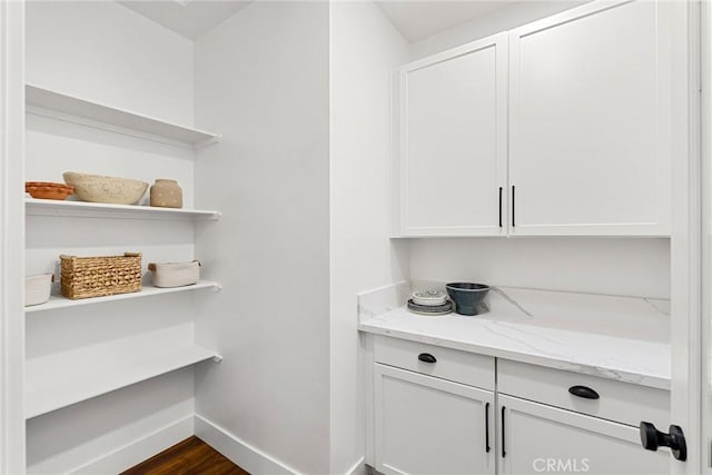 bar with white cabinets, light stone countertops, and dark hardwood / wood-style floors