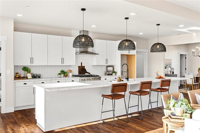 kitchen featuring decorative backsplash, decorative light fixtures, and a large island with sink