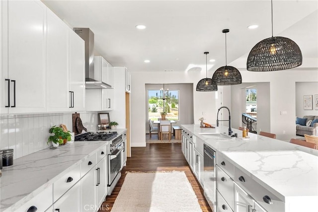 kitchen with backsplash, wall chimney exhaust hood, stainless steel appliances, and white cabinetry