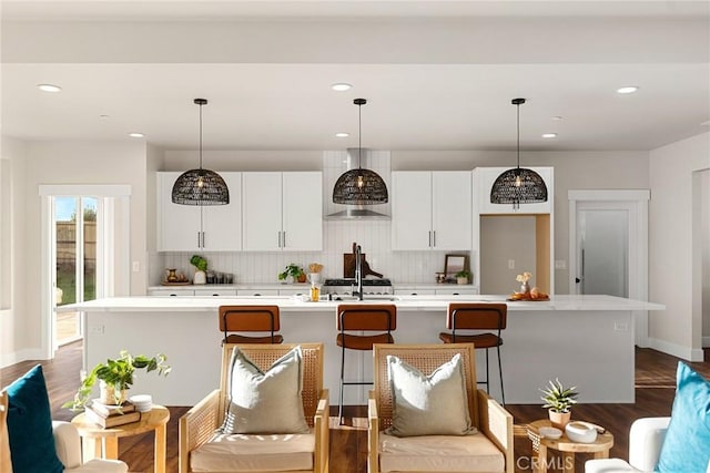 kitchen featuring tasteful backsplash, a breakfast bar, an island with sink, and hanging light fixtures