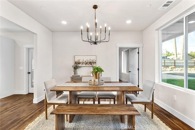 dining area with dark wood-type flooring and a notable chandelier