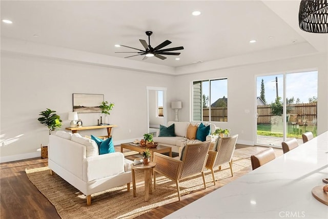 living room with ceiling fan, dark hardwood / wood-style floors, and a raised ceiling