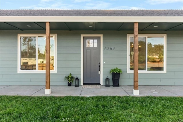 property entrance with covered porch and a lawn