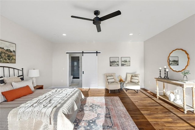 bedroom with ceiling fan, wood-type flooring, and a barn door