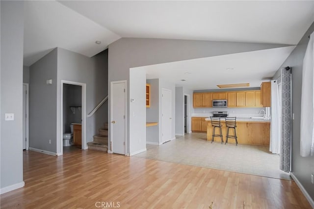 unfurnished living room featuring light hardwood / wood-style floors, high vaulted ceiling, and sink