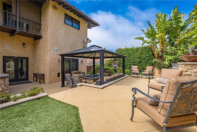 view of patio with an outdoor living space with a fire pit, a gazebo, french doors, and a balcony